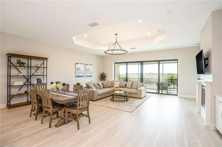 Dining space with a tray ceiling, light wood-type flooring, recessed lighting, and a chandelier