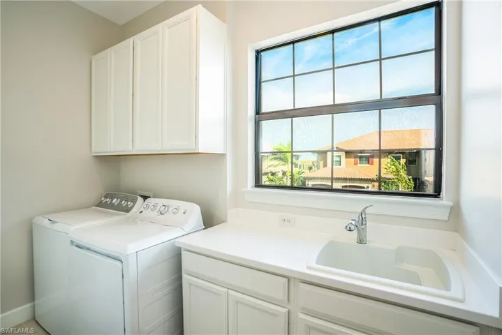 Washroom featuring cabinet space, washing machine and dryer, and healthy amount of natural light