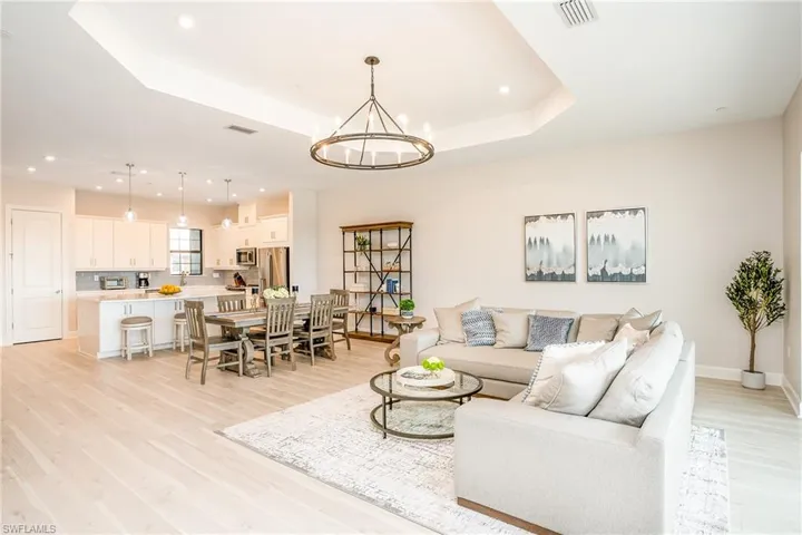 Living area with a tray ceiling, light wood-style flooring, a chandelier, and recessed lighting