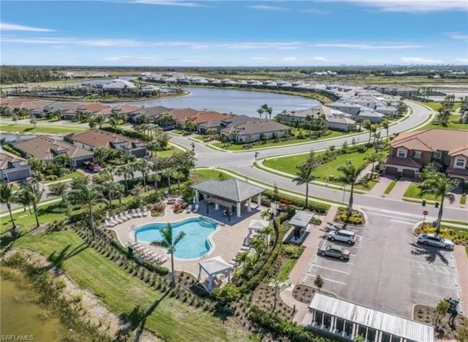 Aerial perspective of suburban area featuring a pool and a large body of water