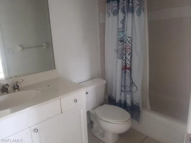 Bathroom with vanity, shower / tub combo, and light tile patterned flooring