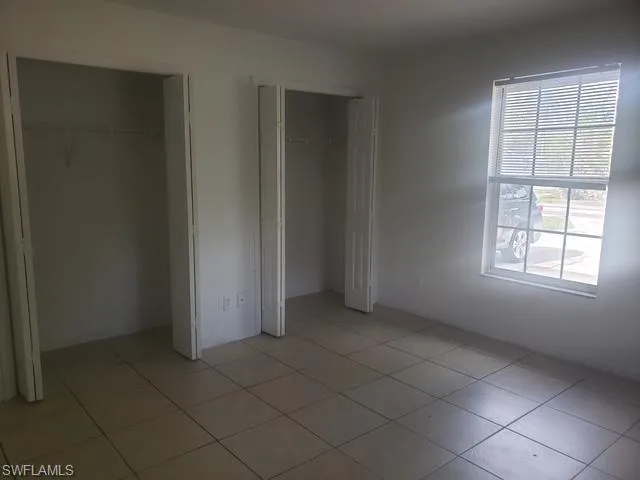 Unfurnished bedroom with multiple closets and light tile patterned floors