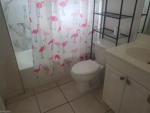 Full bathroom with vanity, shower / bath combination with curtain, and light tile patterned floors