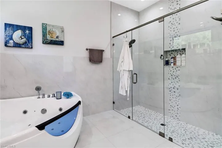 Full bathroom featuring tile walls, a shower stall, a whirlpool tub, and tile patterned floors