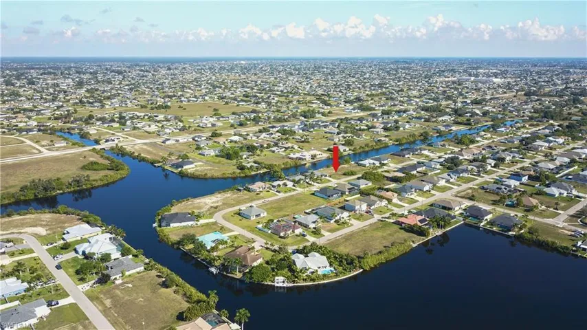 Aerial view of property and surrounding area featuring nearby suburban area and a nearby body of water