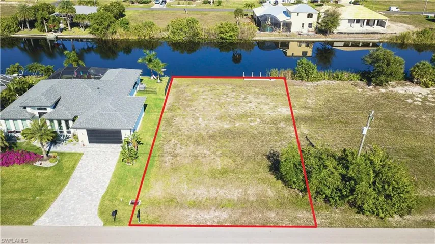 Aerial view of residential area featuring a nearby body of water and property parcel outlined