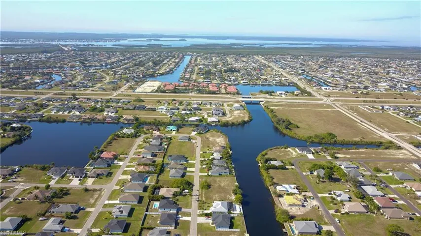 Aerial view of property and surrounding area featuring nearby suburban area and a nearby body of water