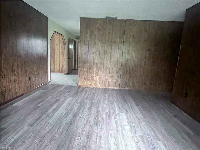 Empty room with wooden walls and light hardwood / wood-style flooring