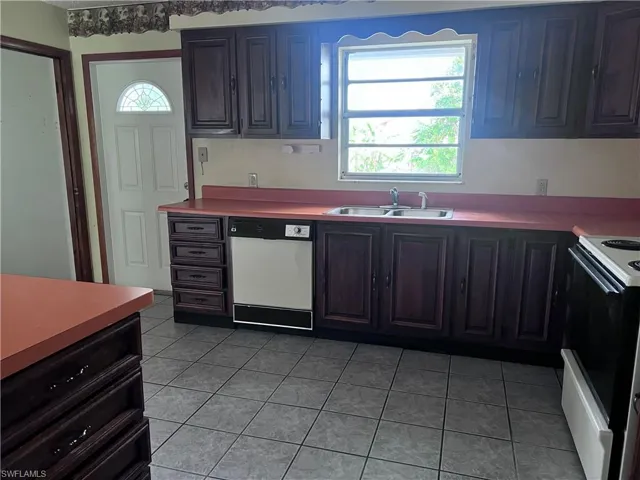 Kitchen featuring sink, white appliances, and light tile floors