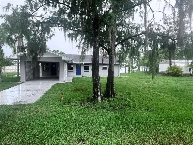 Ranch-style house featuring a carport and a front lawn