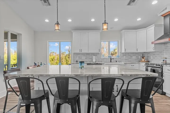 Kitchen with pendant lighting, stainless steel electric stove, a kitchen island, and white cabinets
