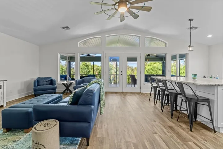 Living room with vaulted ceiling, french doors, ceiling fan, and light wood-type flooring