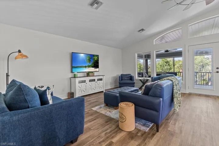 Living room featuring lofted ceiling, dark wood-type flooring, and ceiling fan