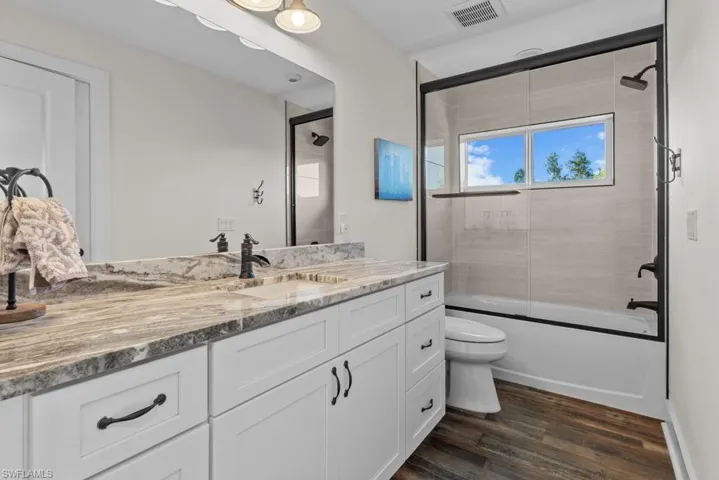 2nd Full bathroom featuring vanity, hardwood / wood-style flooring, enclosed tub / shower combo, and toilet
