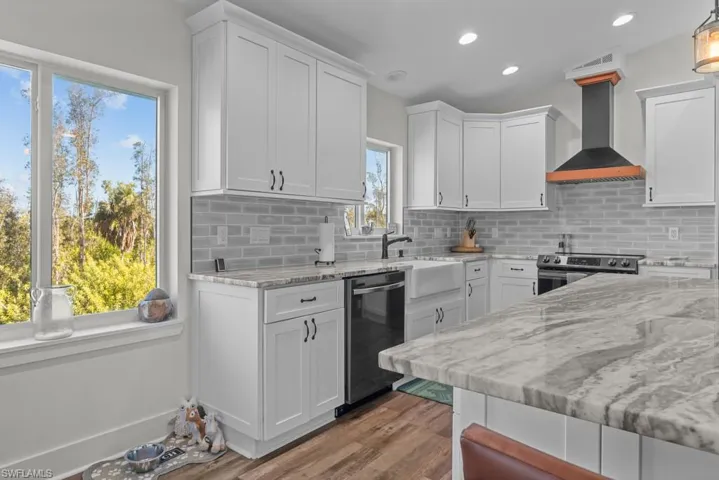Kitchen with white cabinets, stainless steel appliances, and wall chimney range hood
