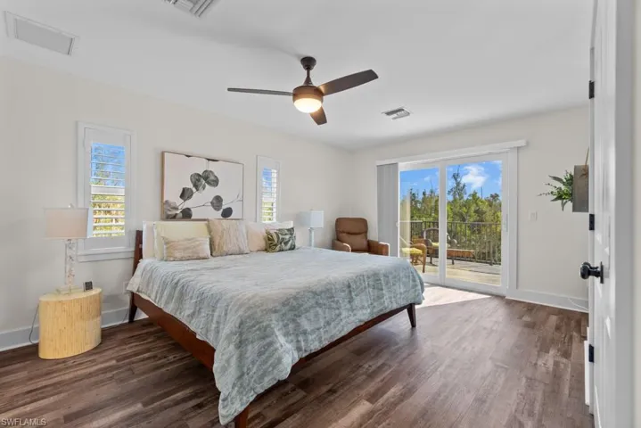 Bedroom with multiple windows, dark wood-type flooring, access to exterior, and ceiling fan