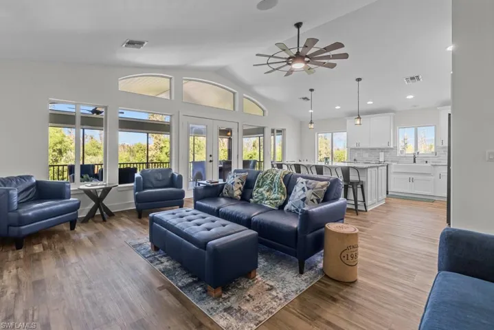Living room with lofted ceiling, sink, light hardwood / wood-style flooring, ceiling fan, and french doors