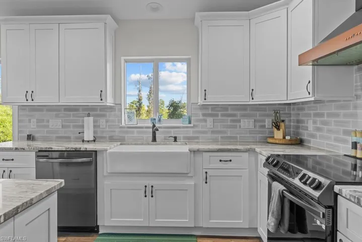 Kitchen with white cabinetry, extractor fan, sink, and dishwasher