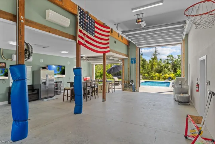 Garage featuring stainless steel refrigerator with ice dispenser and a wall unit AC