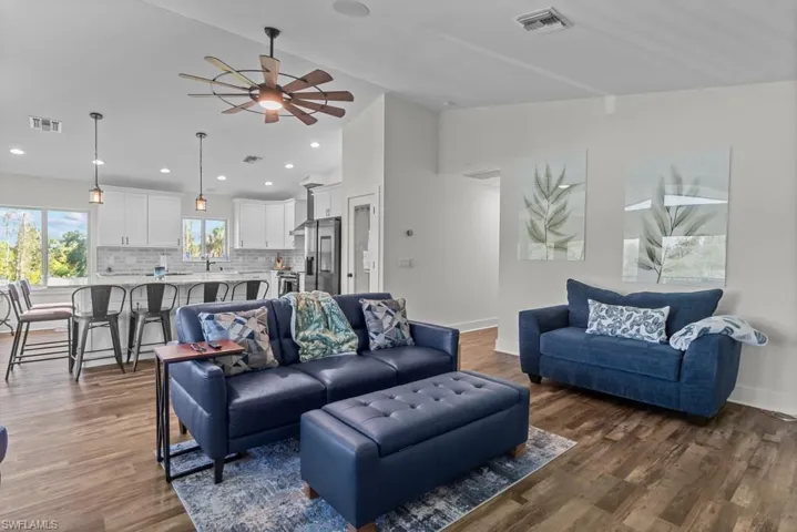 Living room featuring lofted ceiling, dark hardwood / wood-style floors, and ceiling fan