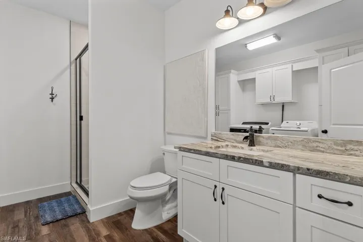 3rd full Bathroom on them Mid-Level featuring a tile shower, vanity, wood-type flooring, and toilet and laundry