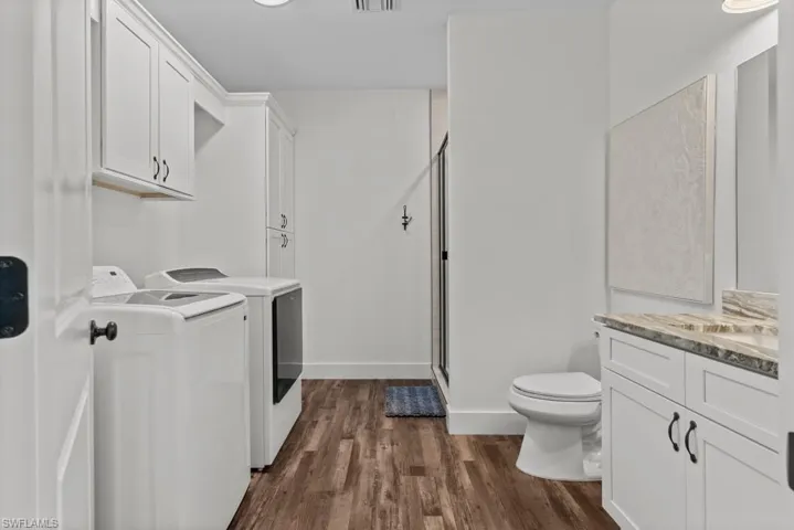 Laundry room featuring washing machine and clothes dryer and dark hardwood / wood-style floors