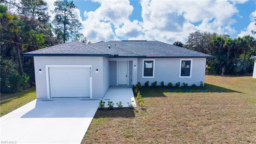 Single story home with a garage, stucco siding, concrete driveway, roof with shingles, and a front yard