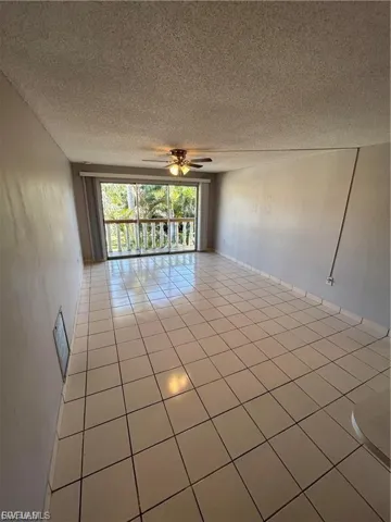 Empty room featuring a textured ceiling, a ceiling fan, and light tile patterned floors