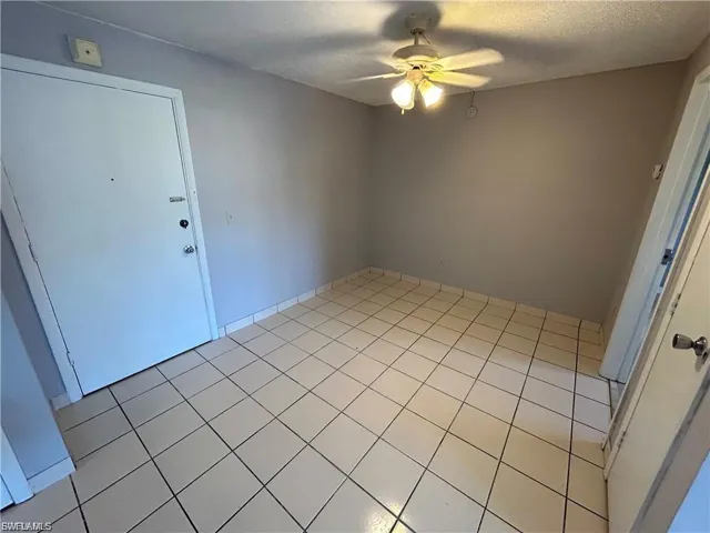 Unfurnished room with light tile patterned flooring, a ceiling fan, and a textured ceiling
