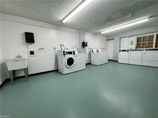 Communal laundry room featuring washer and dryer and a textured ceiling