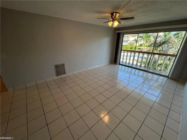 Empty room featuring light tile patterned floors, a textured ceiling, and a ceiling fan