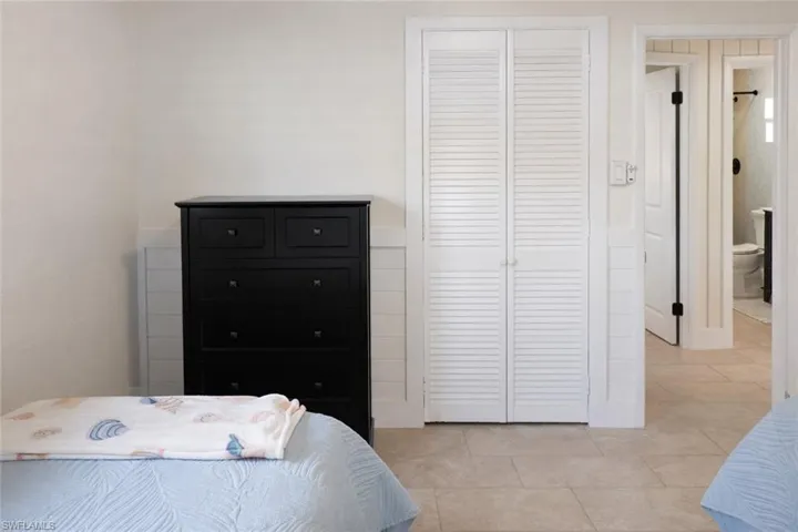 Light-toned tile flooring extends throughout this interior space, featuring white shiplap wainscoting and smooth white walls