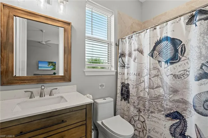3rd bathroom featuring a ceiling fan, toilet, a shower with shower curtain, and vanity