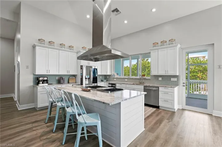 Kitchen featuring a center island, island exhaust hood, white cabinetry, stainless steel appliances, and tasteful backsplash - hood no longer there
