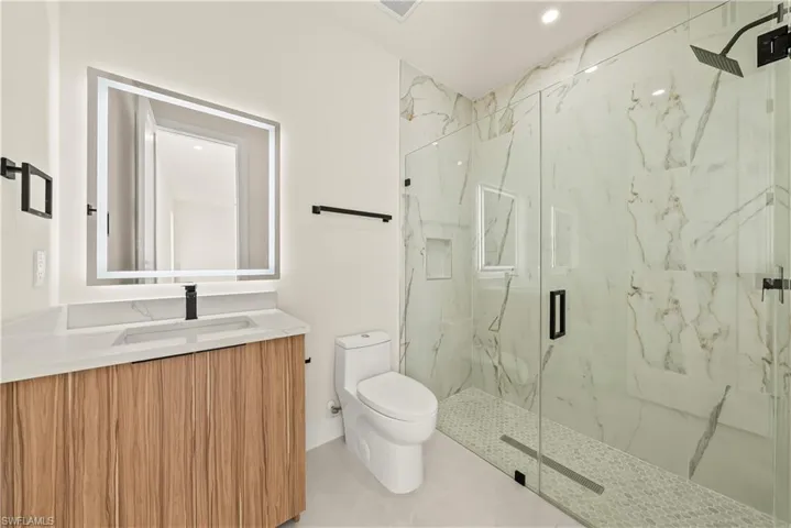 Full bathroom featuring vanity, a marble finish shower, and recessed lighting