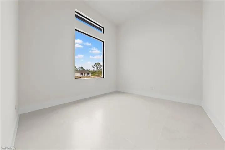 Empty room featuring vaulted ceiling and baseboards