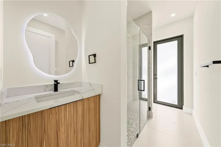 Bathroom featuring a marble finish shower, vanity, and recessed lighting