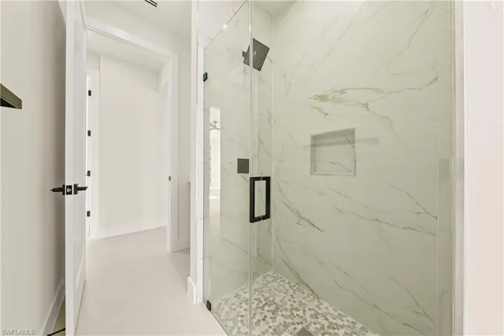 Bathroom featuring a marble finish shower and baseboards