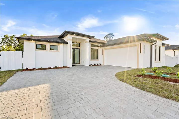 Prairie-style home with stucco siding, decorative driveway, an attached garage, and a gate