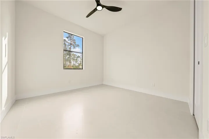 Empty room featuring vaulted ceiling and ceiling fan