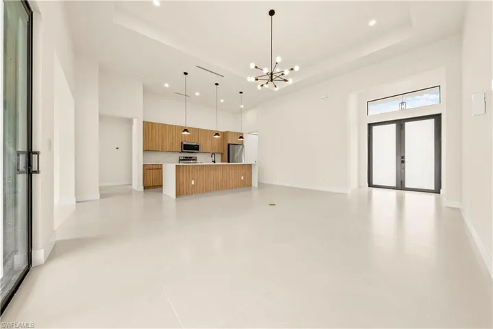 Unfurnished living room featuring hanging lights, a high ceiling, and french doors