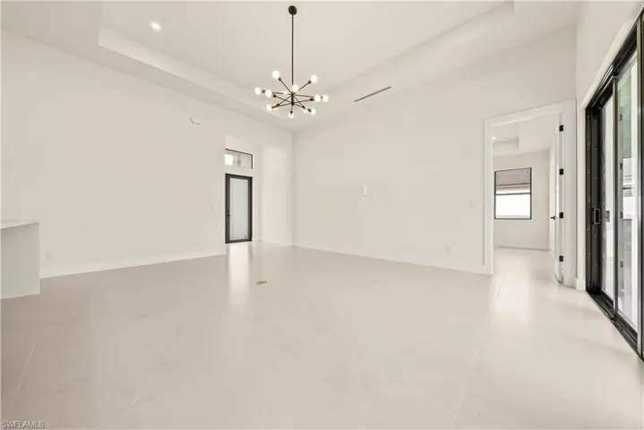 Spare room featuring a raised ceiling and a chandelier