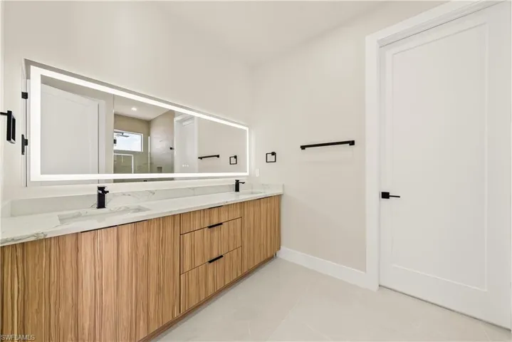 Bathroom featuring a stall shower, double vanity, and light tile patterned floors