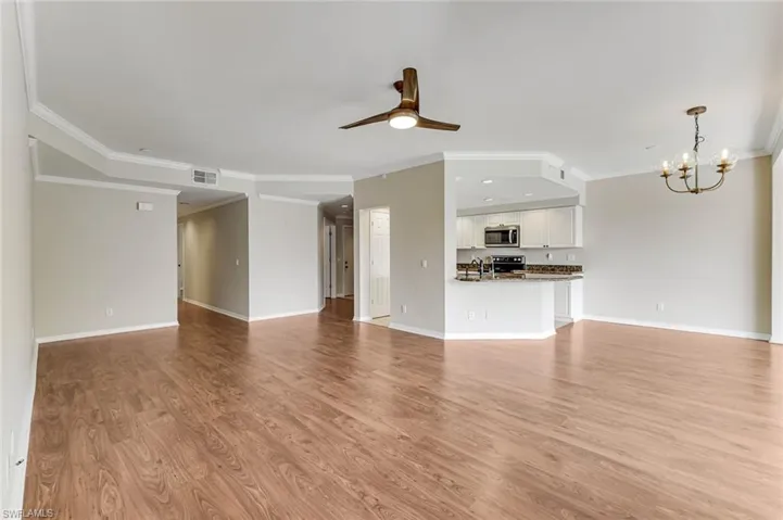 Open-concept living area featuring wood-finish flooring, crown molding, and a ceiling fan