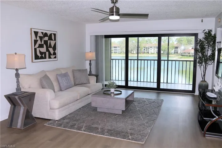 Living area with a textured ceiling, a water view, a ceiling fan, and wood finished floors