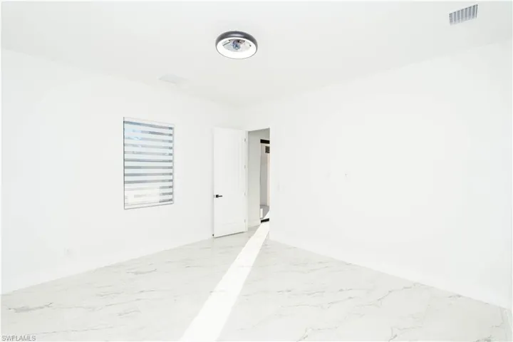 Unfurnished room featuring baseboards and light marble finish floors