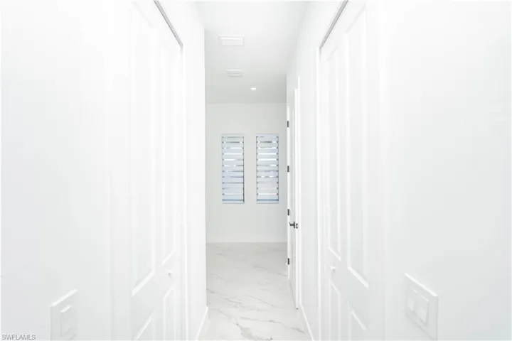 Hall with light marble finish flooring and baseboards