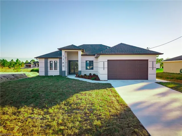 Prairie-style house featuring stucco siding, driveway, a front lawn, a garage, and a shingled roof