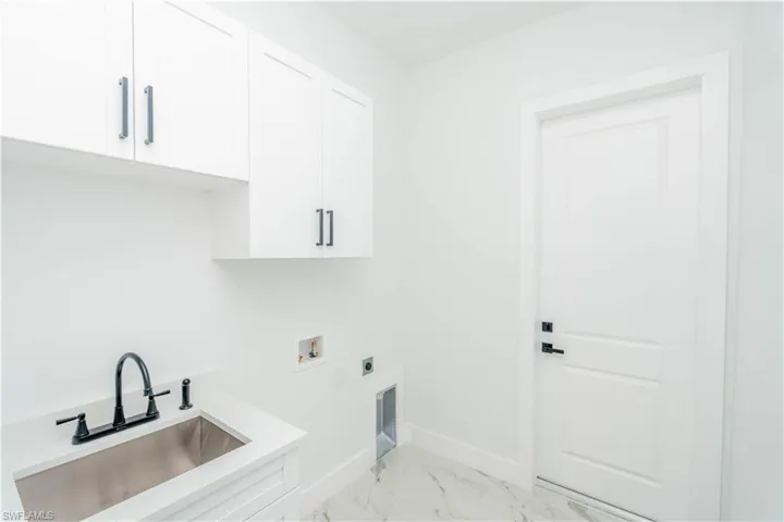 Washroom featuring light marble finish flooring, electric dryer hookup, hookup for a washing machine, and cabinet space