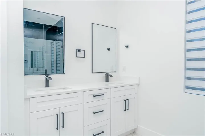 Bathroom with a stall shower, double vanity, and light marble finish floors